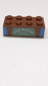 2x4 Stein mit der Aufschrift „TOW MATER“ auf sandgrünem Hintergrundmuster neubraun