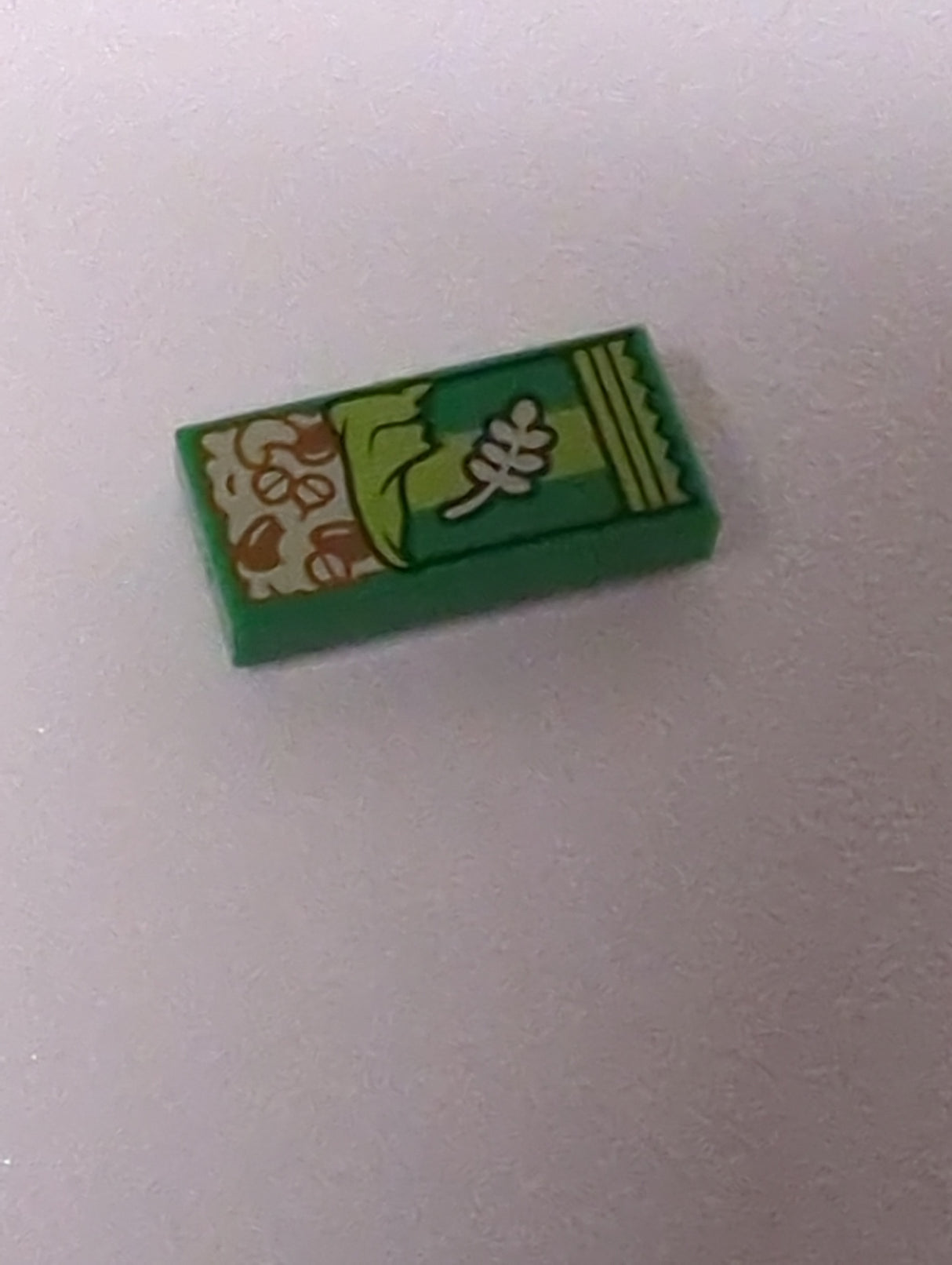 NEU Fliese 1 x 2 mit hellbraunem Müsliriegel mit rötlich braunen Körnern und Samen sowie Limetten-Muster auf der Verpackung grün