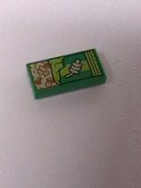 NEU Fliese 1 x 2 mit hellbraunem Müsliriegel mit rötlich braunen Körnern und Samen sowie Limetten-Muster auf der Verpackung grün